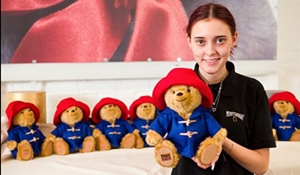 A picture of Honey Chase, who is an apprentice at teddy bear manufacturer Merrythought, holding a Paddington bear teddy.