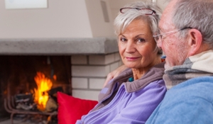 Older man and woman pictured by a fire
