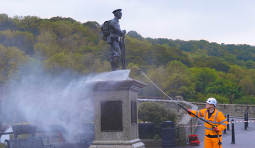 A man jet washing the war memorial in Ironbridge