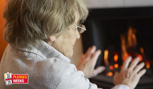 An older person warming their hands by their fire