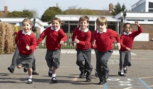 A group of primary school children running on a playground