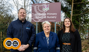 From left to right are Jamie Evans, Councillor Shirley Reynolds and Jo Edwards standing in front of Millbrook Primary School sign