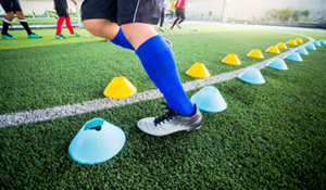 Football training, image from the waist down, football boots, socks and training cones on the pitch