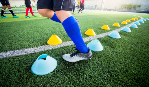 Football training, image from the waist down, football boots, socks and training cones on the pitch