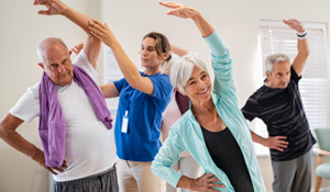 A group of elderly people taking part in an exercise class with an instructor