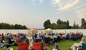 Large seated crowd enjoying an outdoor theatre performance