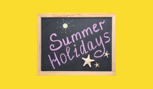 Summer holidays written in chalk on a chalkboard against a yellow background