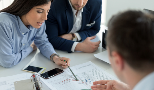 A group of professionals sitting a a desk, reviewing documents together during a business meeting. This image reflects collaboration and business support 