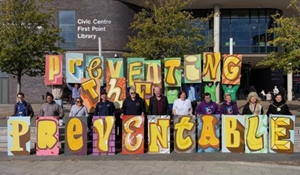 Stall holders hold letter signs to read 'Preventing the Preventable'