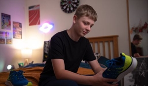 A young person sitting on their bed looking at a new pair of trainers