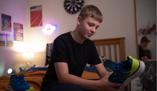 A young person sitting on their bed looking at a new pair of trainers