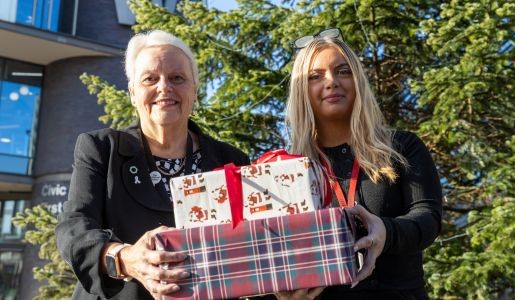 Councillor Shirley Reynolds and Leona Jones, Voice of the Child apprentice at Telford & Wrekin Council holding Christmas presents in front of the Christmas tree in Southwater, Telford.