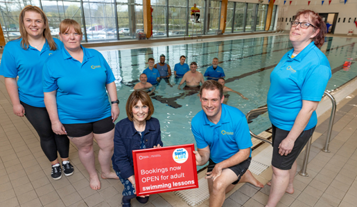 Councillor Angela McClements pictured poolside with swimming instructors and adult swimmers in the water 