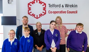 Adults with a group of children who had taken part in school debates in the Council chamber