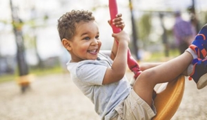 A young boy smiling while on a swing