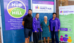 Four people standing in front of Telford and Wrekin Family Hub signage, including a man, two women in purple, and a woman.