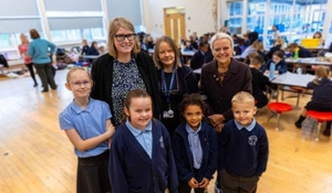 Group photo of staff and Shirley with staff and children at William Reynolds Primary School